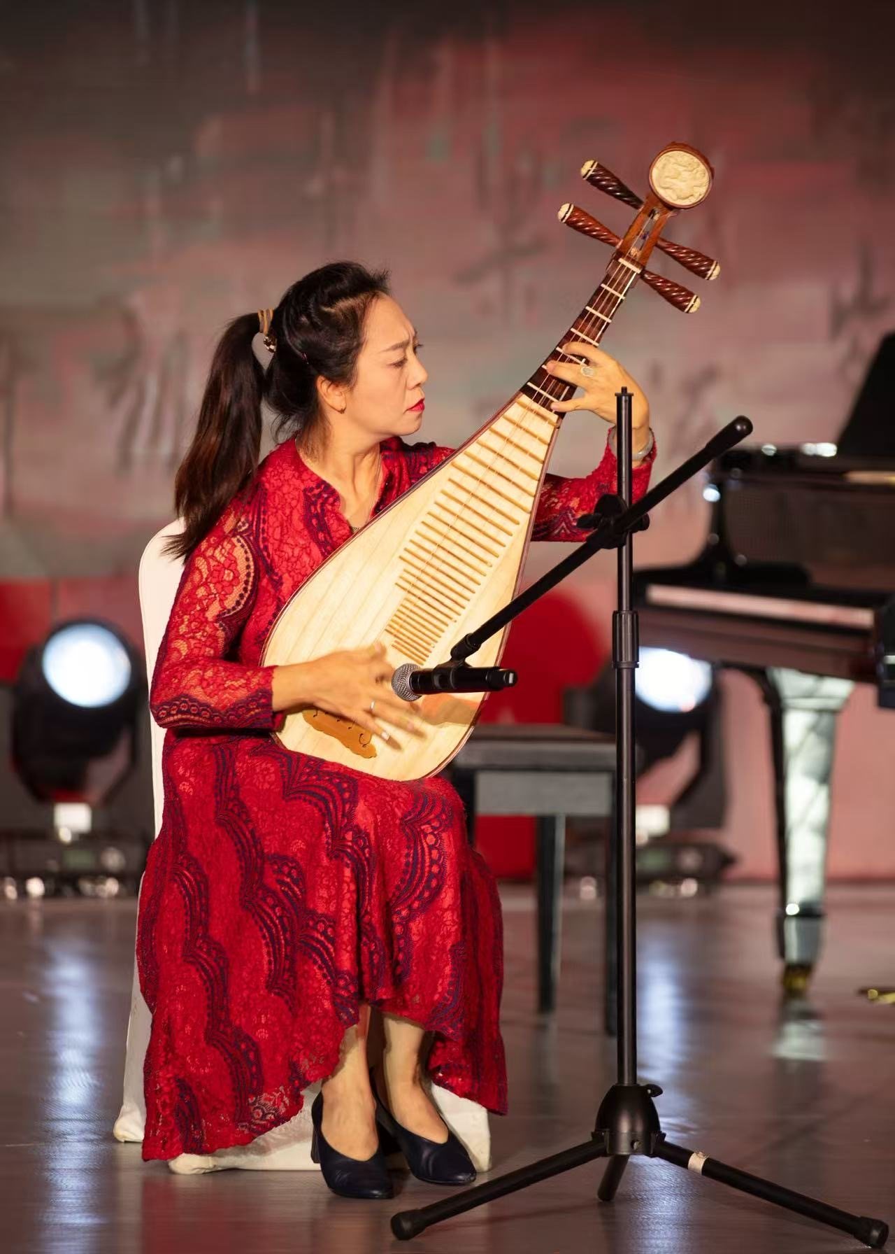 Sijia Lou spielt Pipa in rotem Kleid bei einem Konzertauftritt